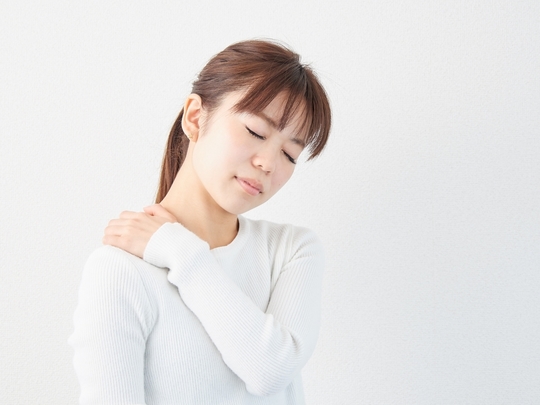 肩首のこりで肩を押さえる女性の写真