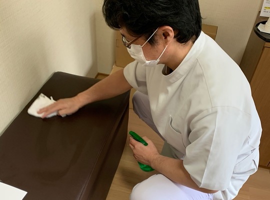 白衣で待合室の椅子を清掃する