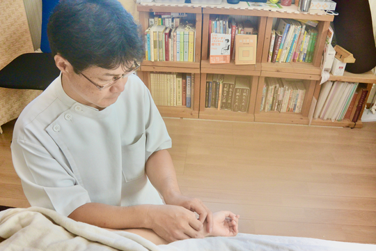手のツボに丁寧に鍼を施術する様子