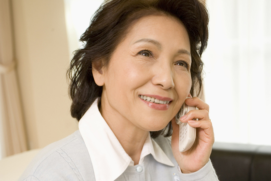笑顔で電話問い合わせをしている高齢女性