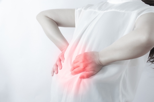 痛みで腰を抱えて疼くまる女性